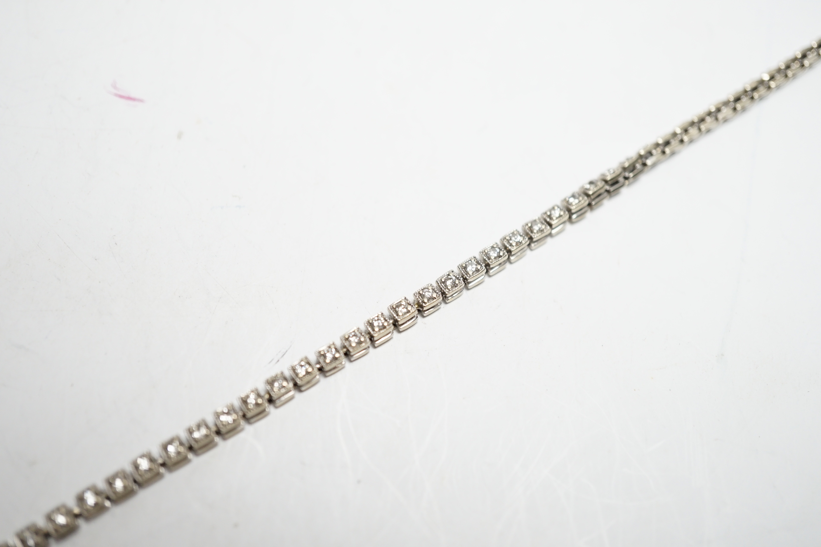 A 750 white metal and diamond line bracelet, set with sixty small stones, 20.8cm, gross weight 12 grams.